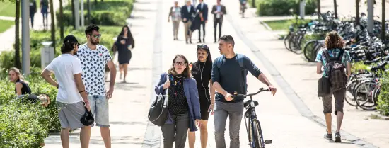 Students walking on campus with a bike