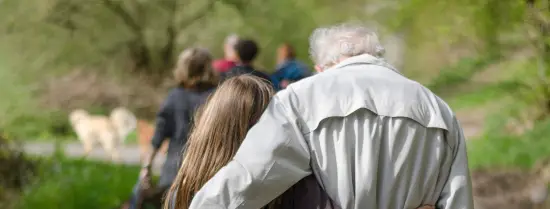 Opa en kleindochter lopen omarmd op straat