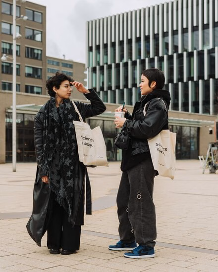 Two prospective students stand in the plaza on campus Woudestein chatting to each other.