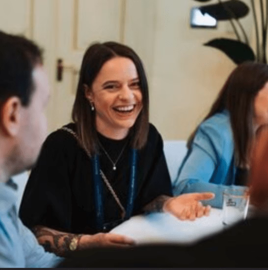 brunette vrouw in het zwart gekleed rondom de tafel met mensen