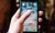 A hand holding a smartphone with music apps such as Spotify