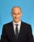 Portrait picture of Adam Komisarof with green tie and blue background