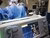 Doctors are working in an operating room in blue coats.
