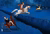 horse stopping in front of cliff, while other horse jumps over to catch gold deer