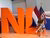 Smiling woman sitting on the letters NL. A Dutch and an American flag stand behind her.