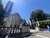 Classical university building entrance with stone statue, blue banners, green trees.