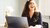 Breeduit lachende collega achter haar laptopscherm