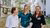 Three women standing arm and arm and smiling into the camera