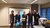 Five people stand side by side with a cake.