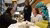 Three students are talking around a table full of creative supplies