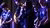 People performing on instruments and a person in the middle singing in the microphone