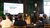 person giving a presentation on a stage using a Powerpoint slide