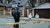 Two cops and two people in white plastic suits investigating behind a yellow 'stop' banner