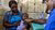 A South-African child sits on mothers lap and gets checked by a doctor.