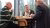 Drie mannelijke aanwezigen zijn in gesprek tijdens het lunchen.