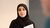 Warda Belabas looks into the camera as she holds papers.