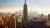 A panoramic view of the New York skyline at sunrise, with the Empire State Building prominently displayed.