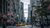 A busy New York street with tall buildings, yellow taxis, pedestrians and American flags.
