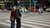 Two old people walking arm and arm on a zebra crossing.