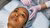 A person lying down on a doctors chair wearing a blue cap getting an injection in their forehead