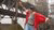 women with red jacket dancing with arms sideways at an industrial dock