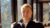 Young blond man with his legs crossed, sitting in a room with a lot windows