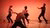 four dancers on stage. One on their knees in the fron. All tinted red. 