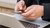 Hands typing on smartphone next to open laptop.