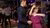 Couple dancing closely on a crowded dance floor under colorful lights