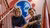 Two coworkers seated on red metal stairs in front of a globe mural and “Take care!” wall text