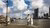 Person standing on waterfront promenade near Erasmus Bridge and Rotterdam skyline under clouds
