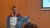Man at MIE 2026 podium with projection screen behind, audience in foreground