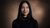 Smiling woman with long black hair against warm brown backdrop