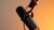 Black studio microphone mounted on adjustable arm against warm orange wall