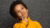 Young Black boy in yellow sweater pondering math formulas on chalkboard background