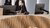 Reception counter with wavy wooden facade, two screens and staff in black holding a mug
