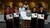 Seven people on stage holding certificates and an oversized check, three in academic robes
