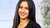 Person with long dark hair smiling in a modern office setting