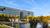 Modern glass office buildings beside a reflecting pond with fountain and autumn trees