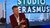 Television host in red blazer gestures on set with STUDIO ERASMUS logo and city skyline
