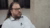 Man with long hair and beard, glasses and white shirt, speaking in interview setting.