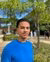 Male student with dark hair, and a blue sweater looking into the camera