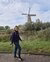 Portretfoto van Marja Oberink, ze is aan het wandelen in de natuur en passeert een molen.