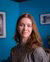 Annelisa looking into the camera in front of a blue cubic