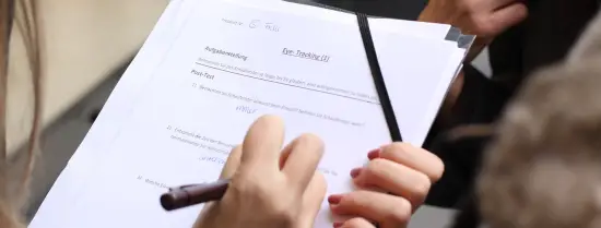 person holding a pen and paper to write on their survey 