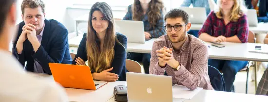 Studenten achter laptops in collegezaal 