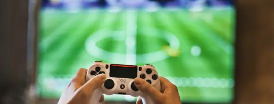 Holding a controller to play soccer on tv