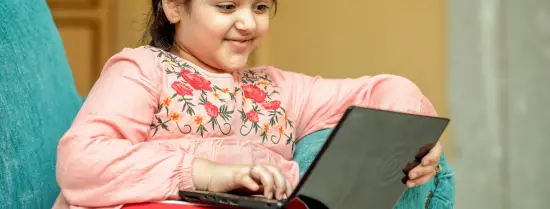 Meisje kijkt op haar laptop en lacht 