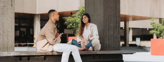Students sitting on a bench on campus and chatting with each other