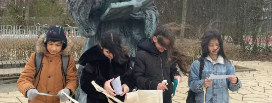 Children doing a scavenger hunt on our campus at Erasmus statue